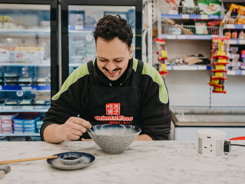 A man eating a bowl of dumplings in a cooking class.